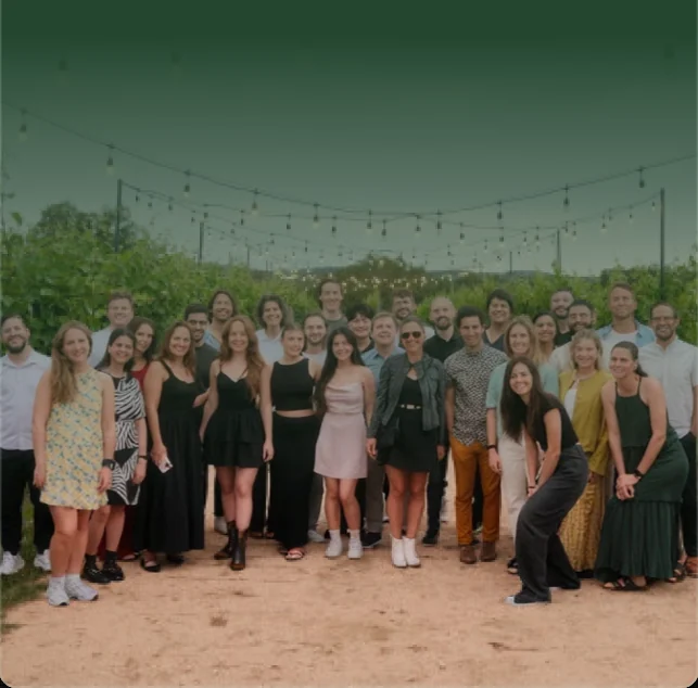 A group photo of the Chameleon team gathered outdoors at an evening event with string lights.